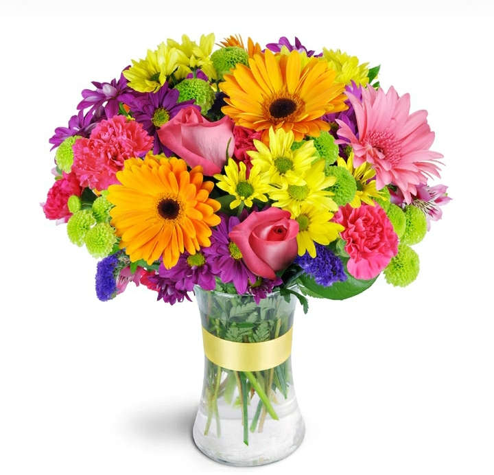 Colorful bouquet of gerbera daisies, roses, and carnations in a glass vase