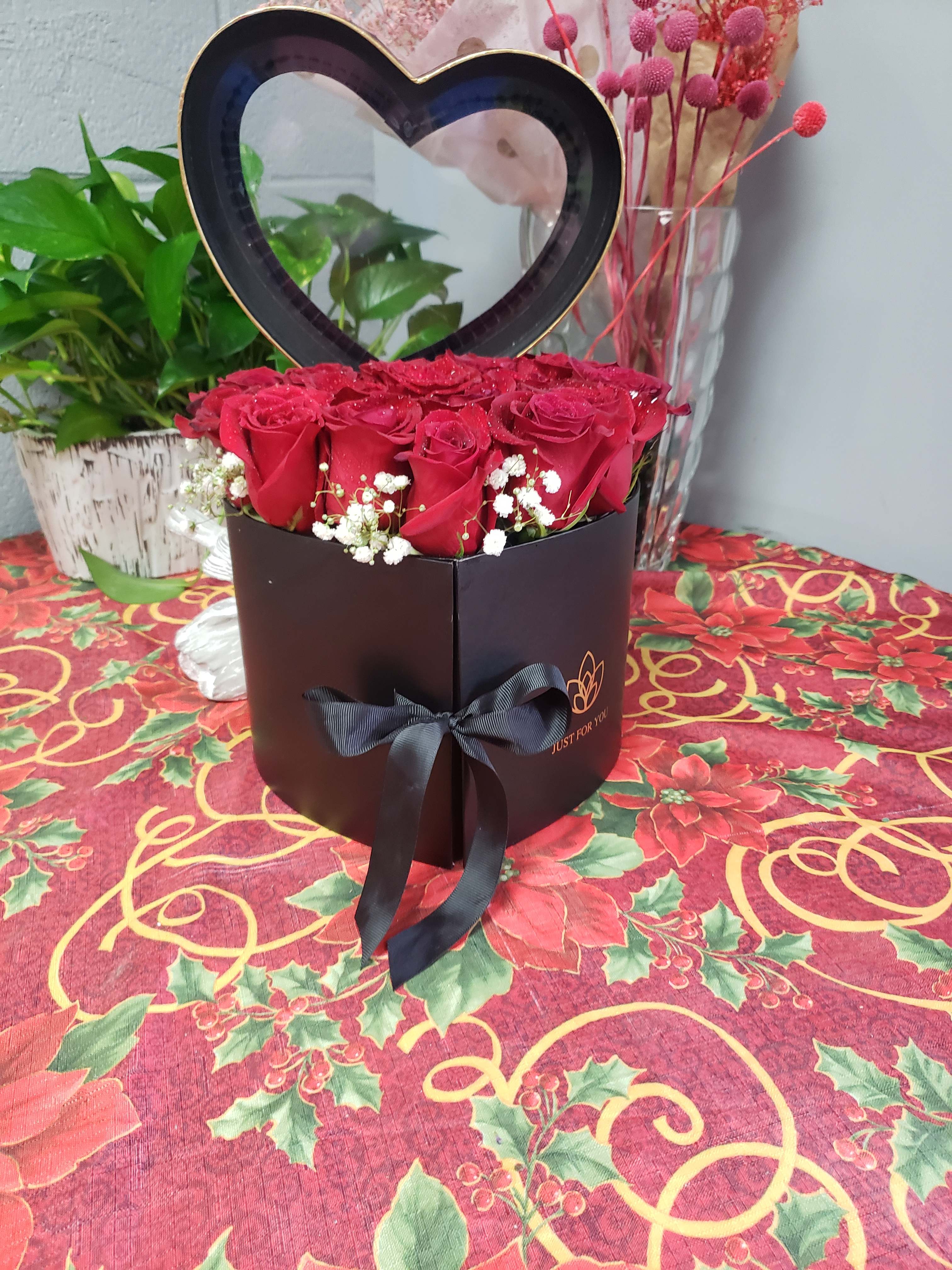 Red roses in a heart-shaped box with a black ribbon