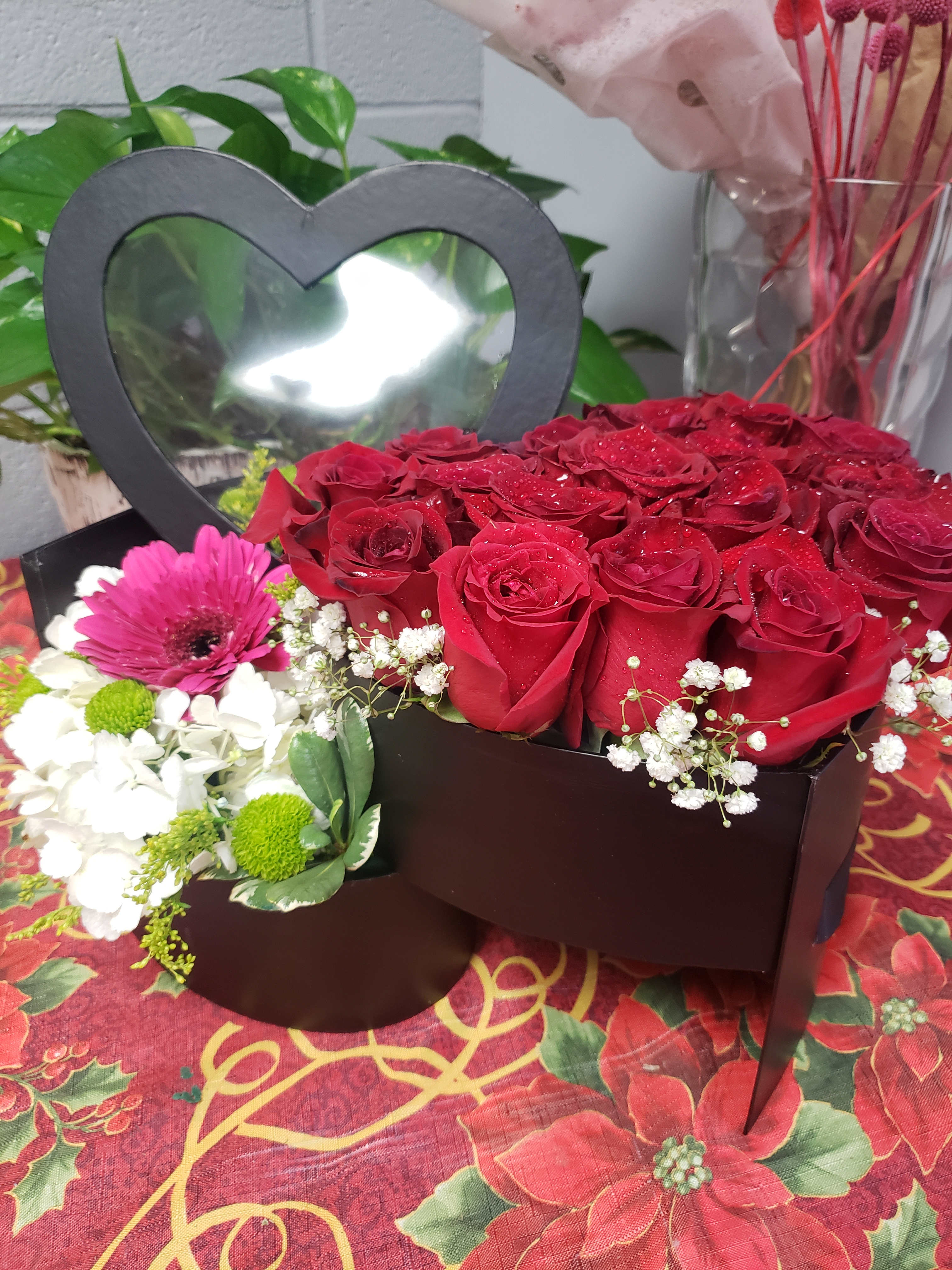 Red roses in a heart-shaped box with white and pink flowers