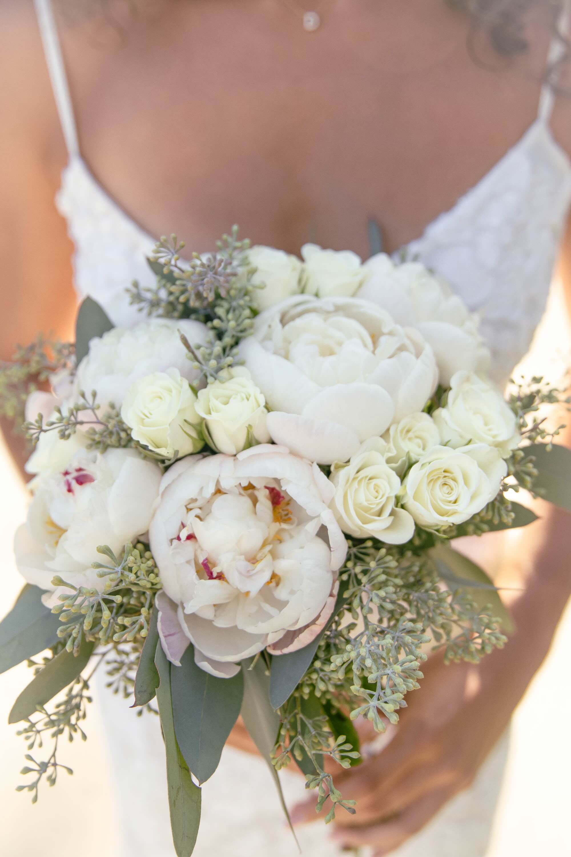 Bride holding a white bouquet of peonies and roses