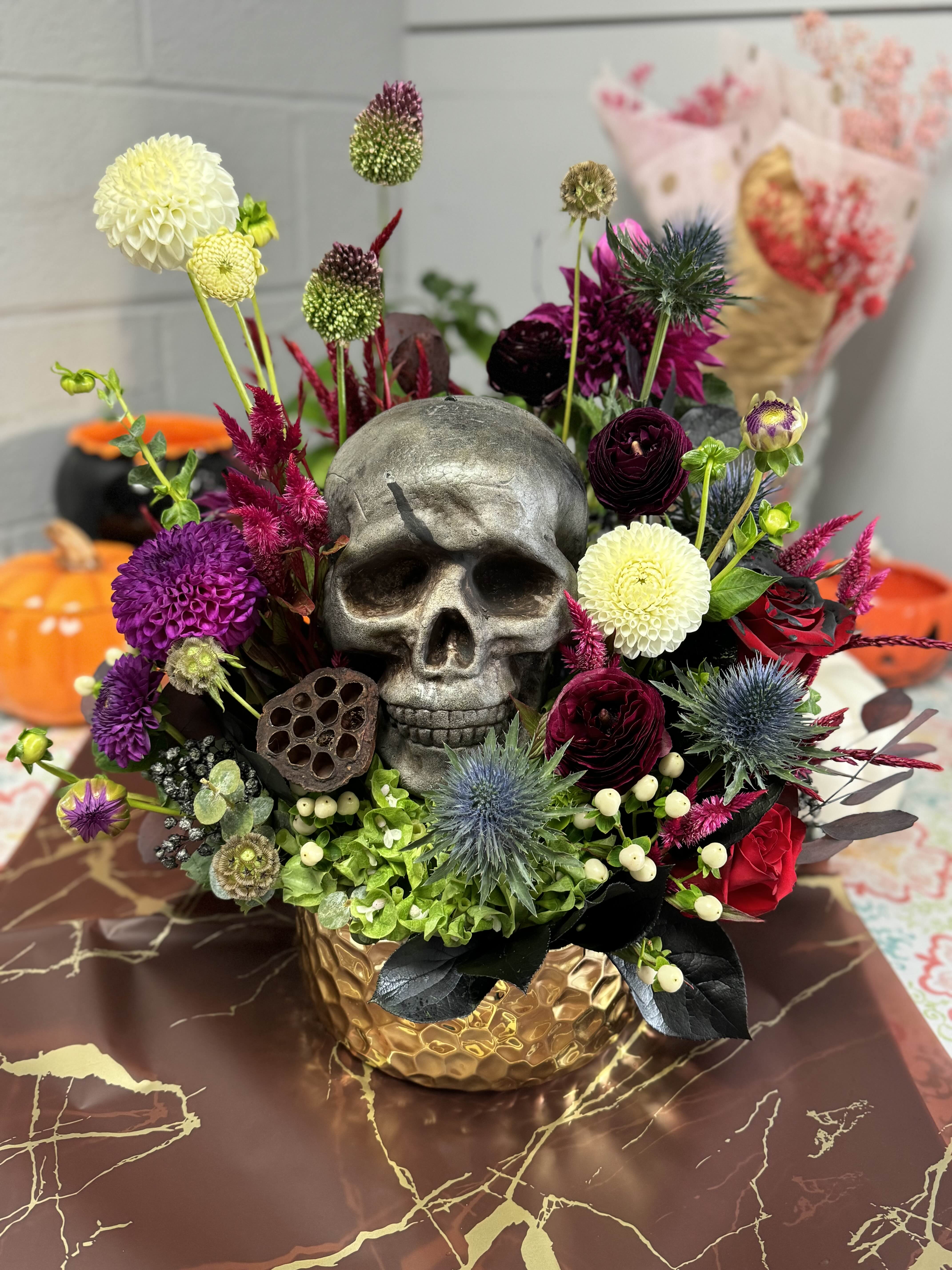 Skull centerpiece with purple and white flowers in a gold vase