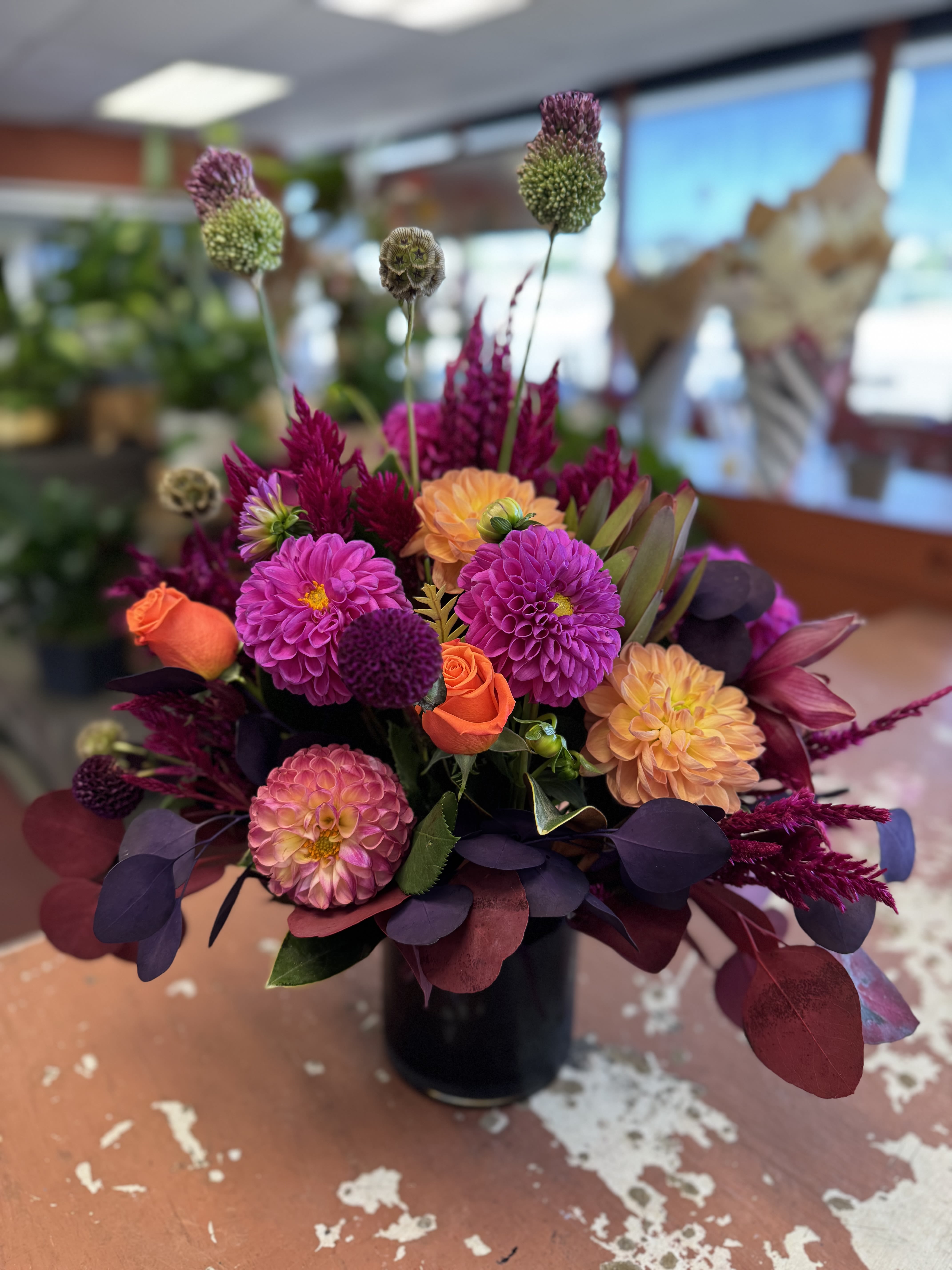 Bright mixed bouquet in a black vase with pink, orange, and purple blooms