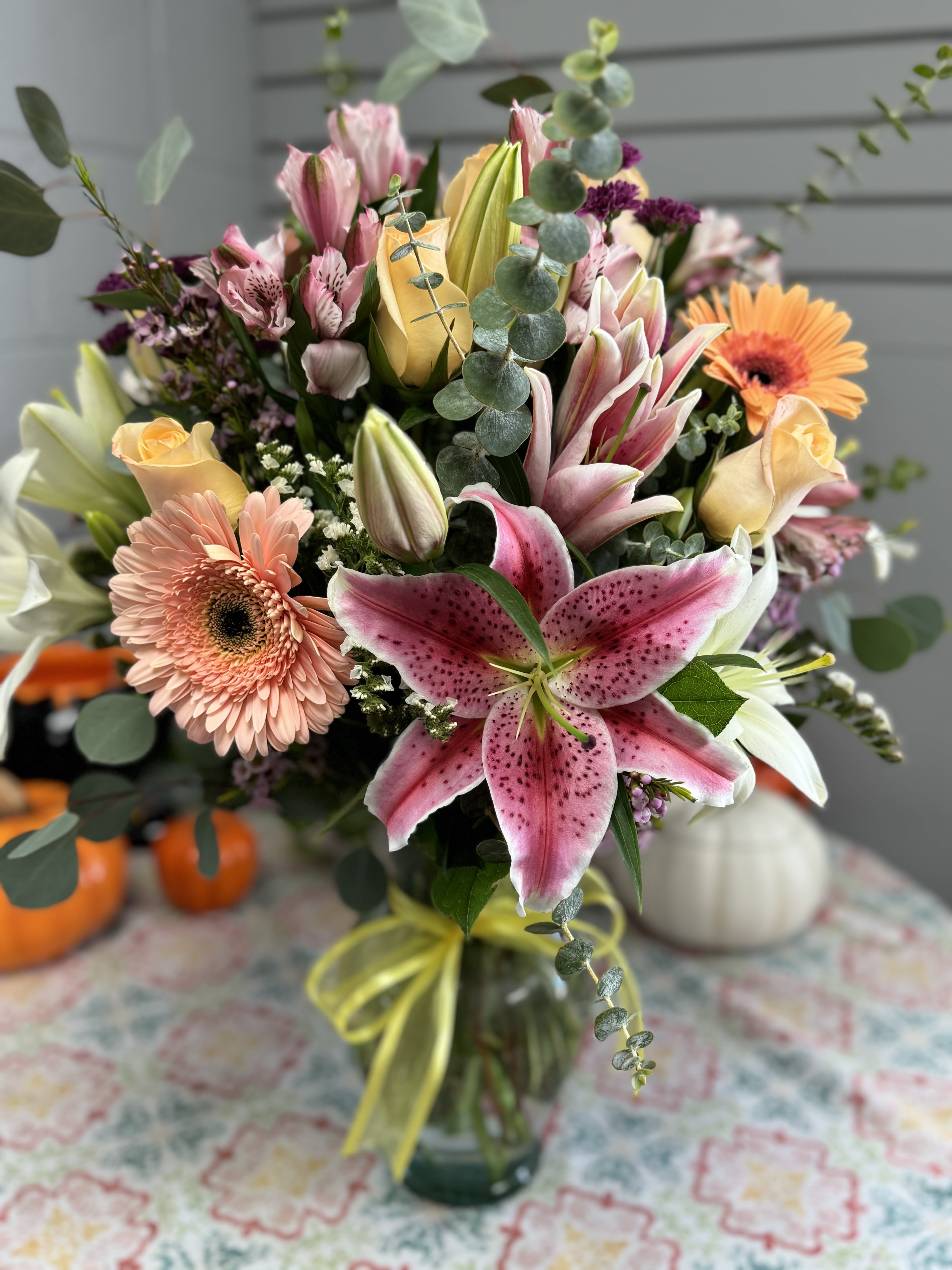 Mixed bouquet with pink lilies, roses, and gerbera daisies in a glass vase