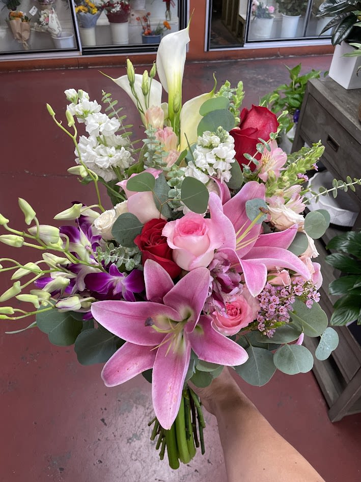 Handheld bouquet of pink lilies, roses, and white calla lilies