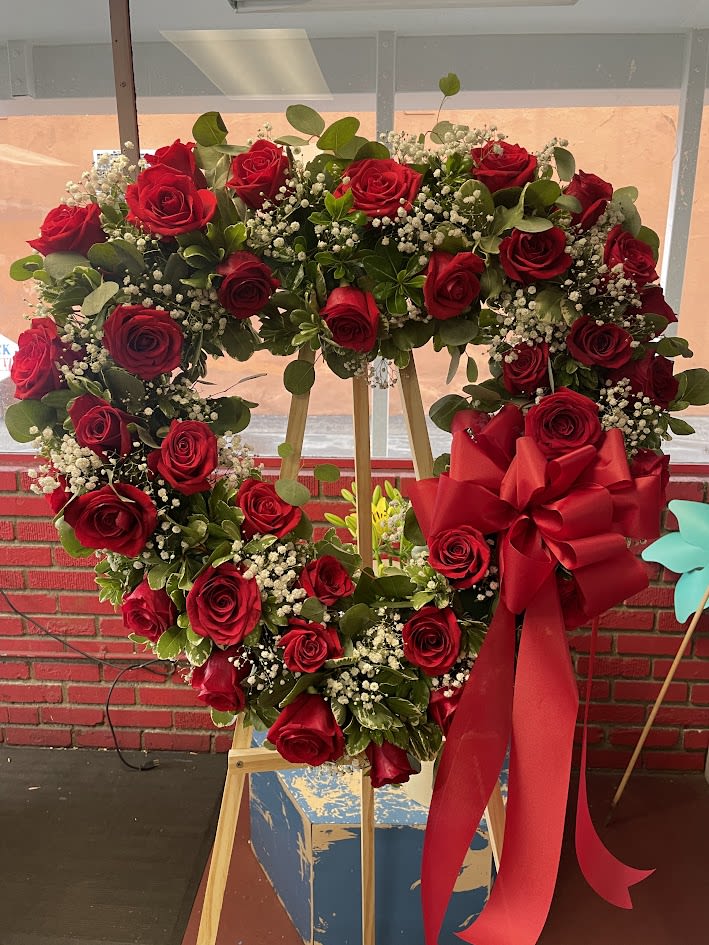 Heart-shaped wreath of red roses with a large red bow