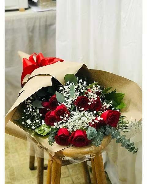Bouquet of red roses with baby's breath wrapped in tan paper