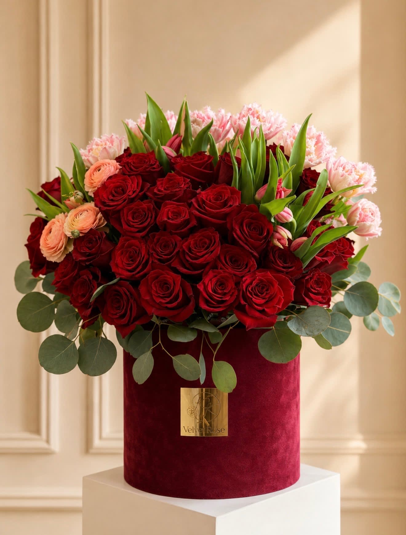 Red roses and pink flowers arranged in a velvet hat box