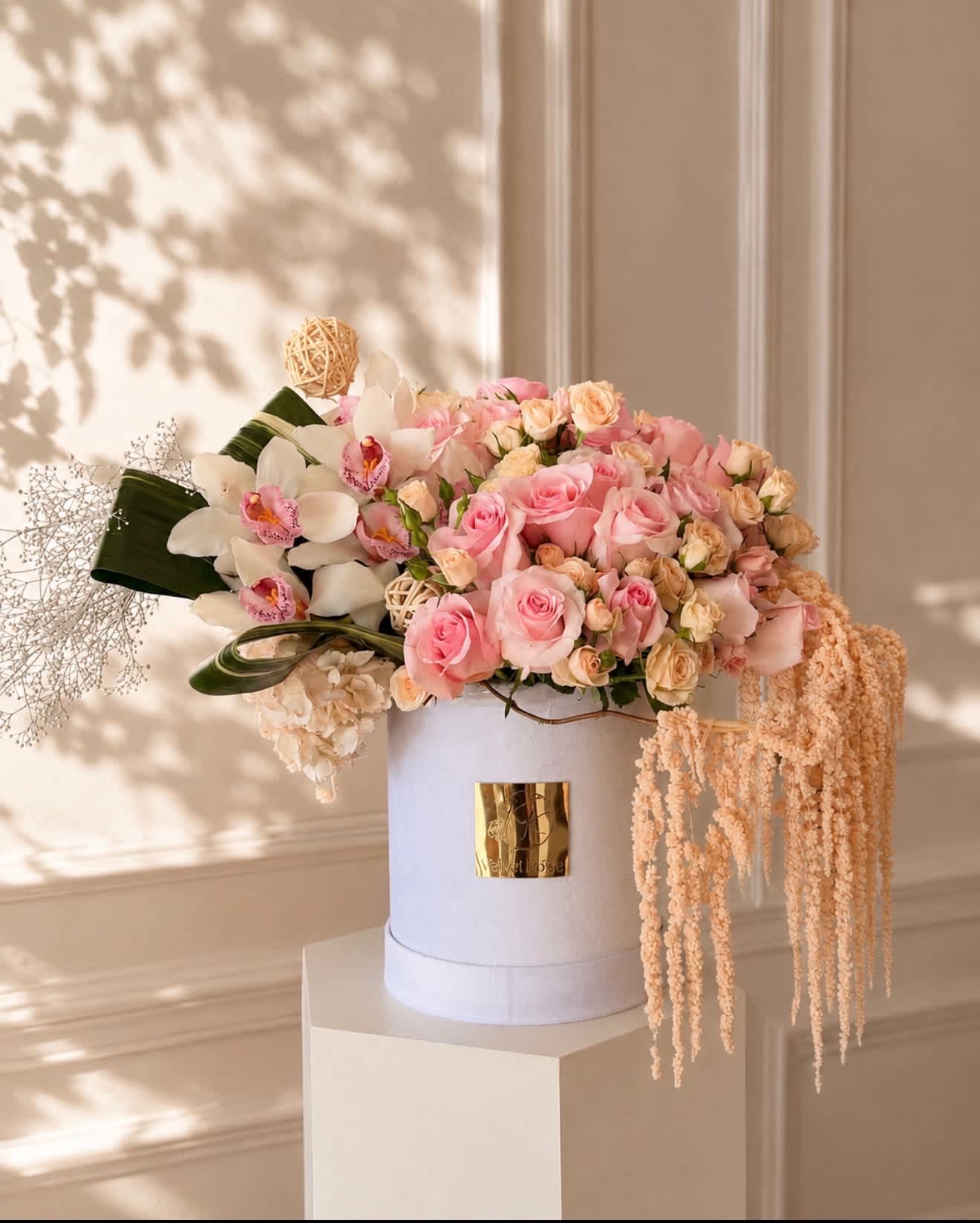 Pink roses and white orchids arranged in a white hat box