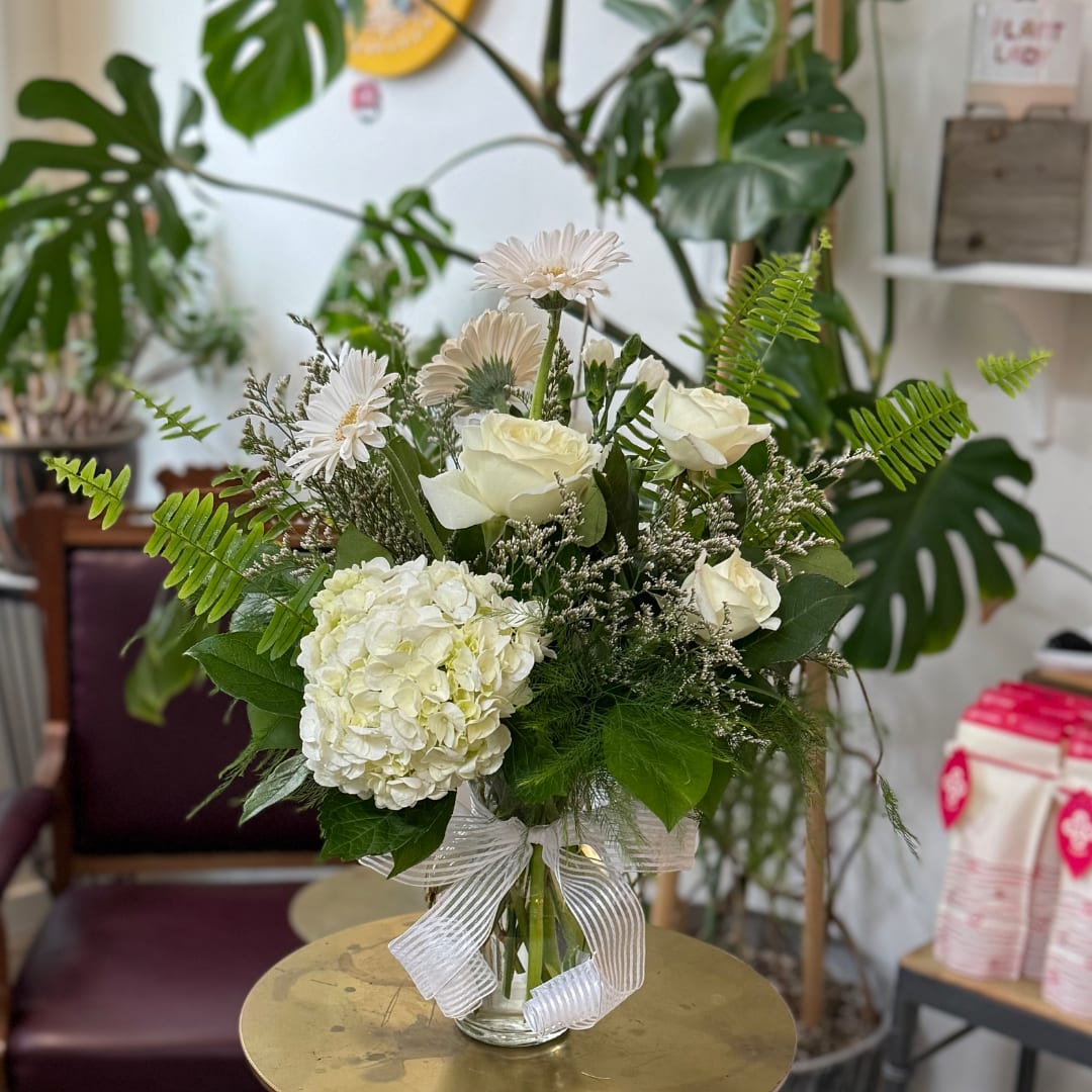White roses and hydrangea in a glass vase with a ribbon
