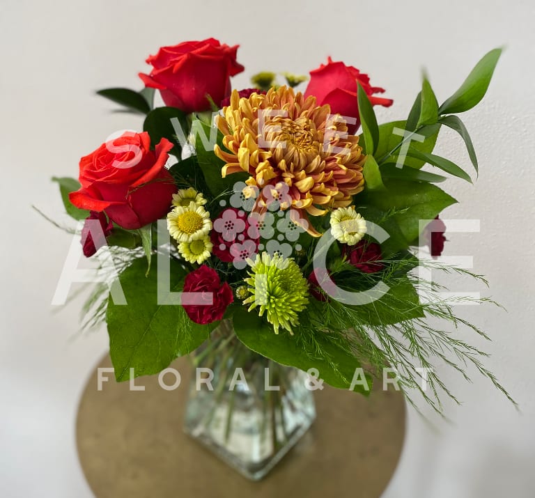 Bouquet of red roses and mixed mums in a glass vase