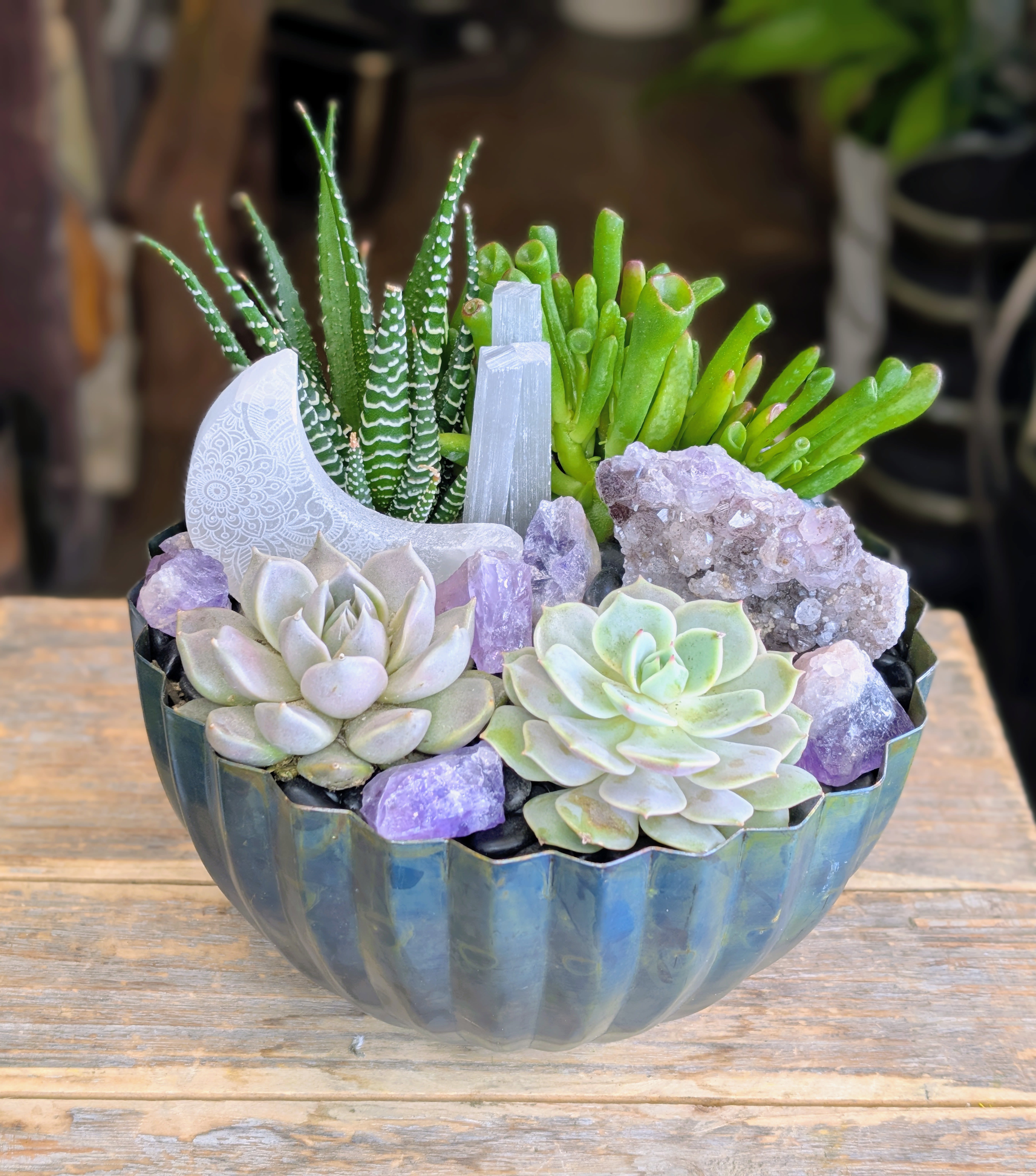 Succulent arrangement in a blue bowl with purple crystals