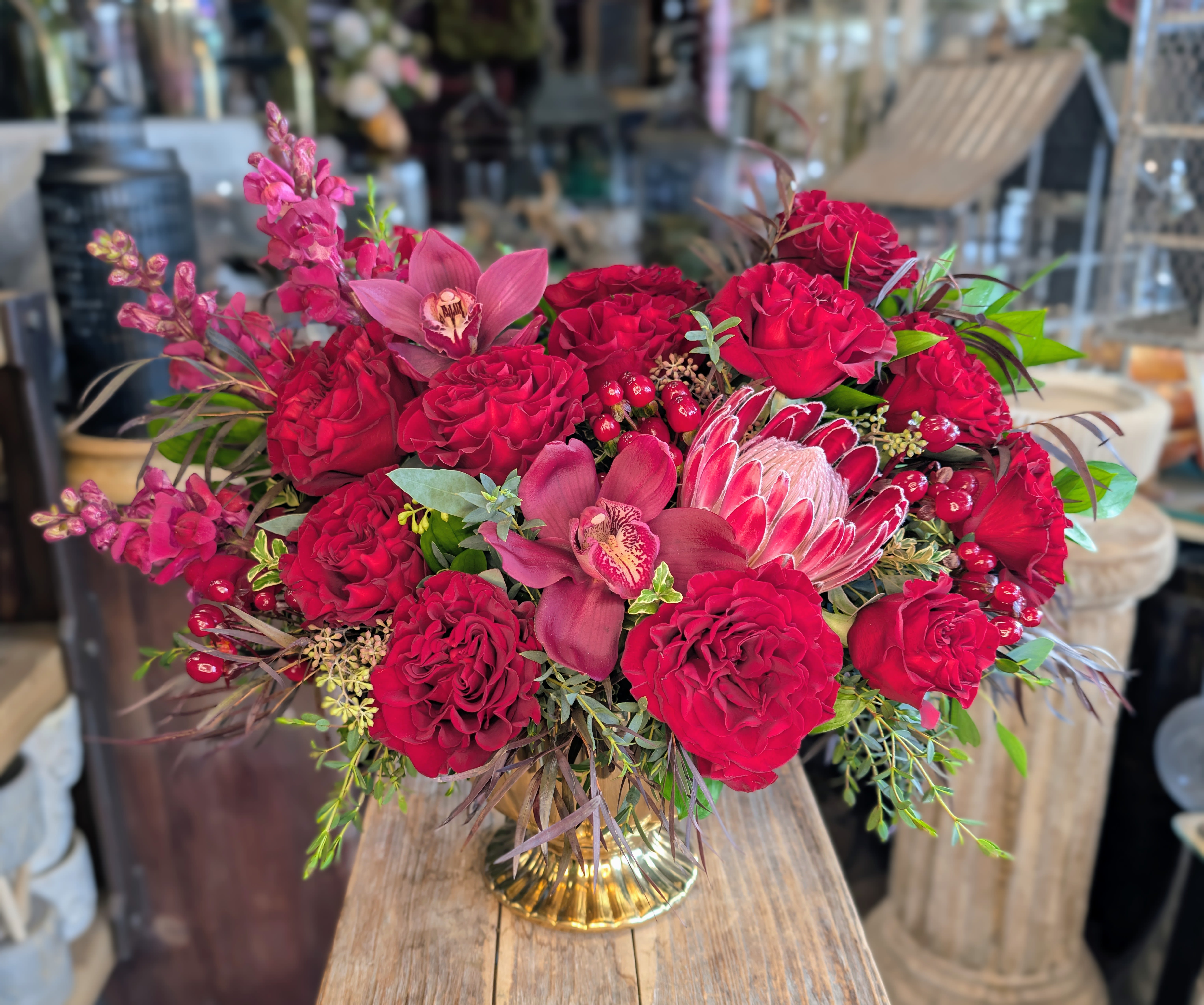 Red rose bouquet with pink orchids in a gold vase