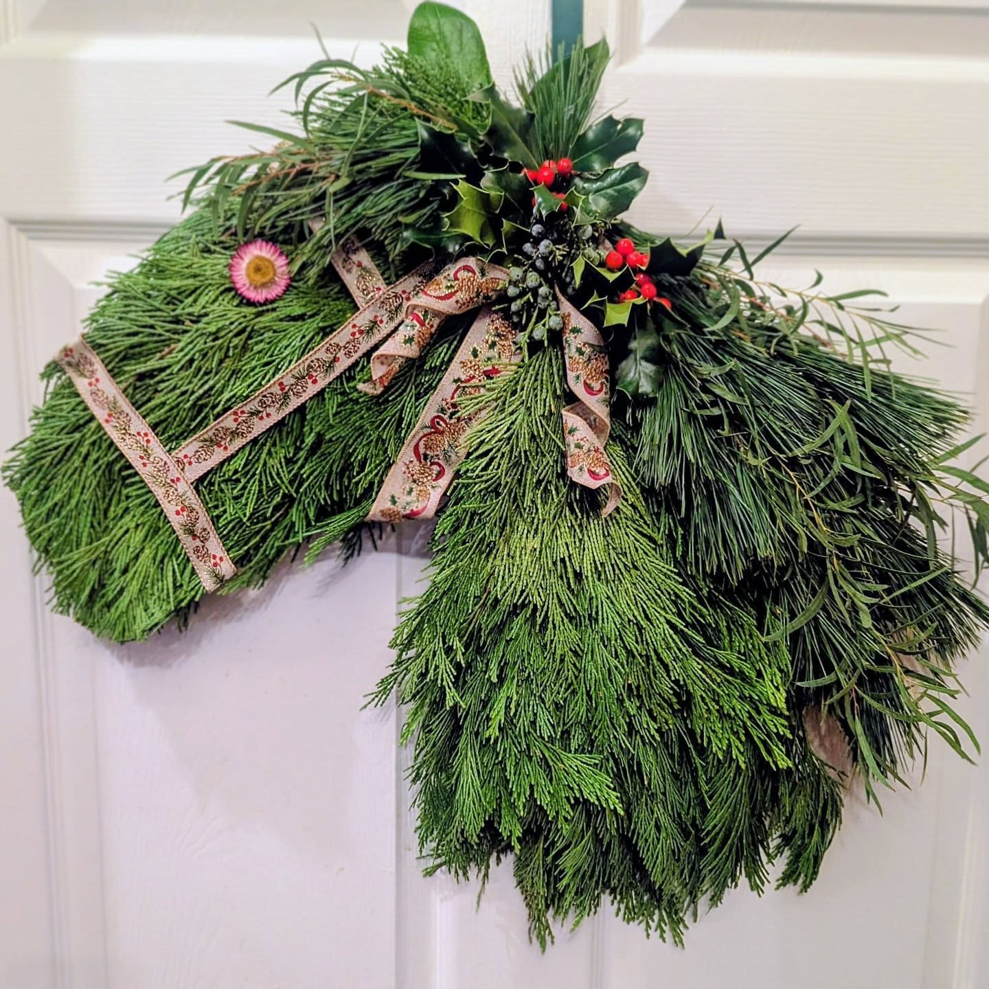 Horse head door swag made of evergreen branches with ribbon and red berries