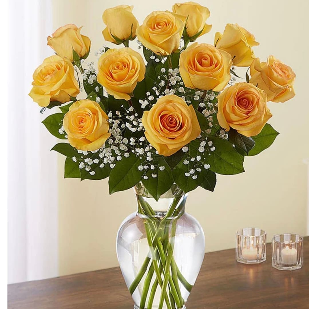 Yellow roses arranged in a clear glass vase with baby's breath