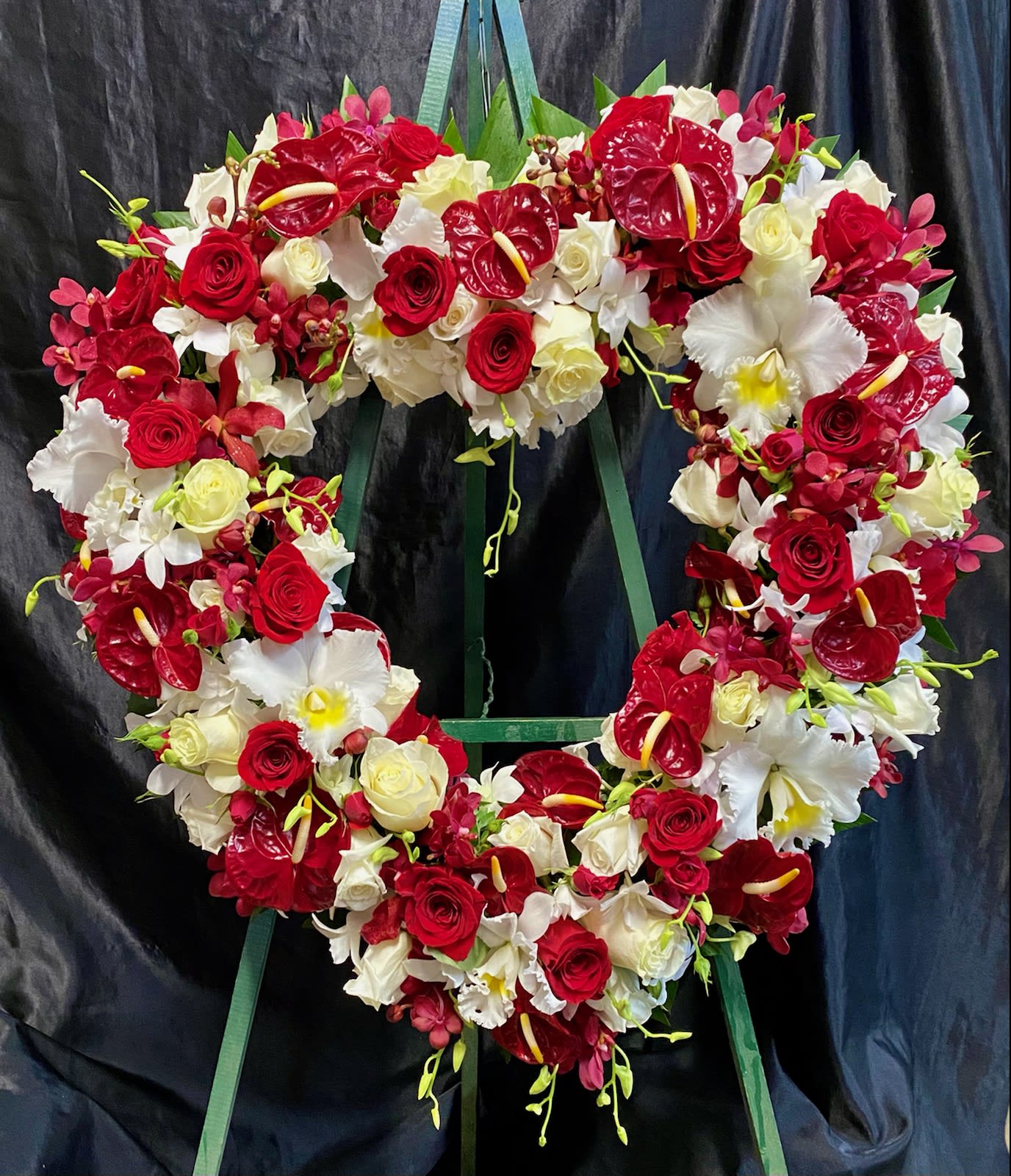 Heart-shaped floral wreath with red and white roses and orchids