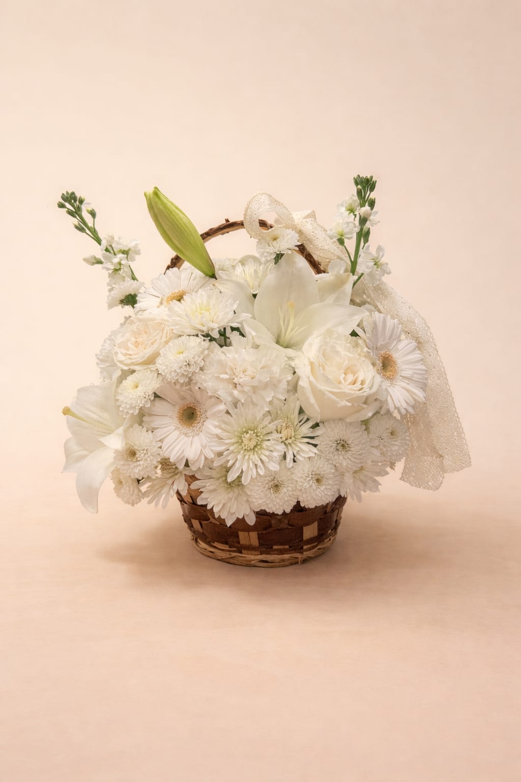 White floral basket arrangement with lilies, roses, and daisies