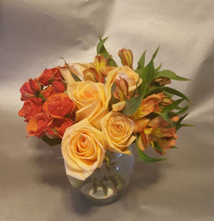 Bouquet of peach and orange roses in a clear glass vase