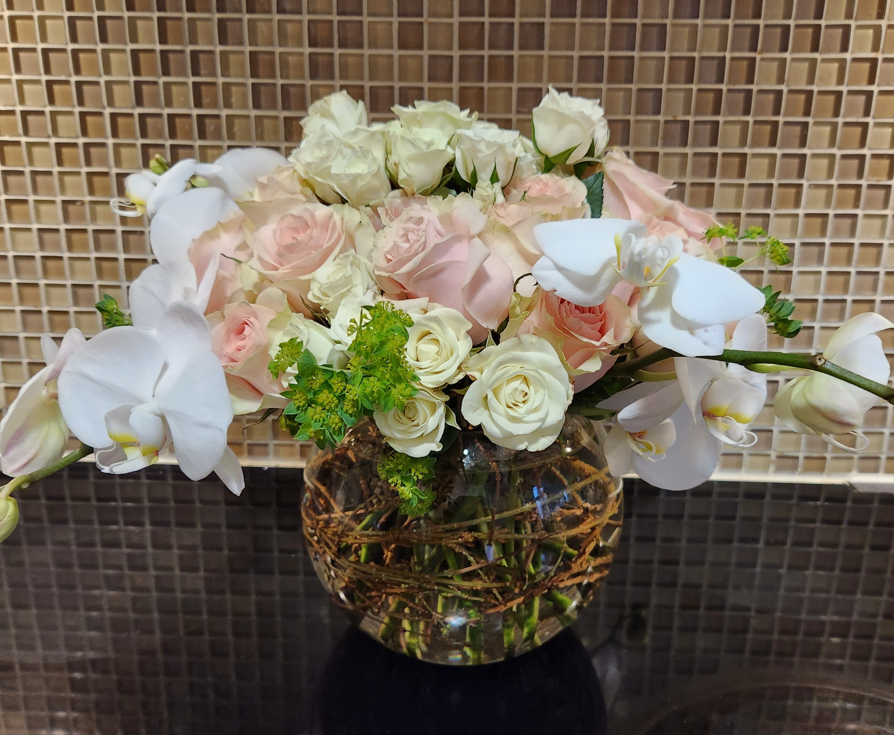 White orchids and pale roses arranged in a glass vase