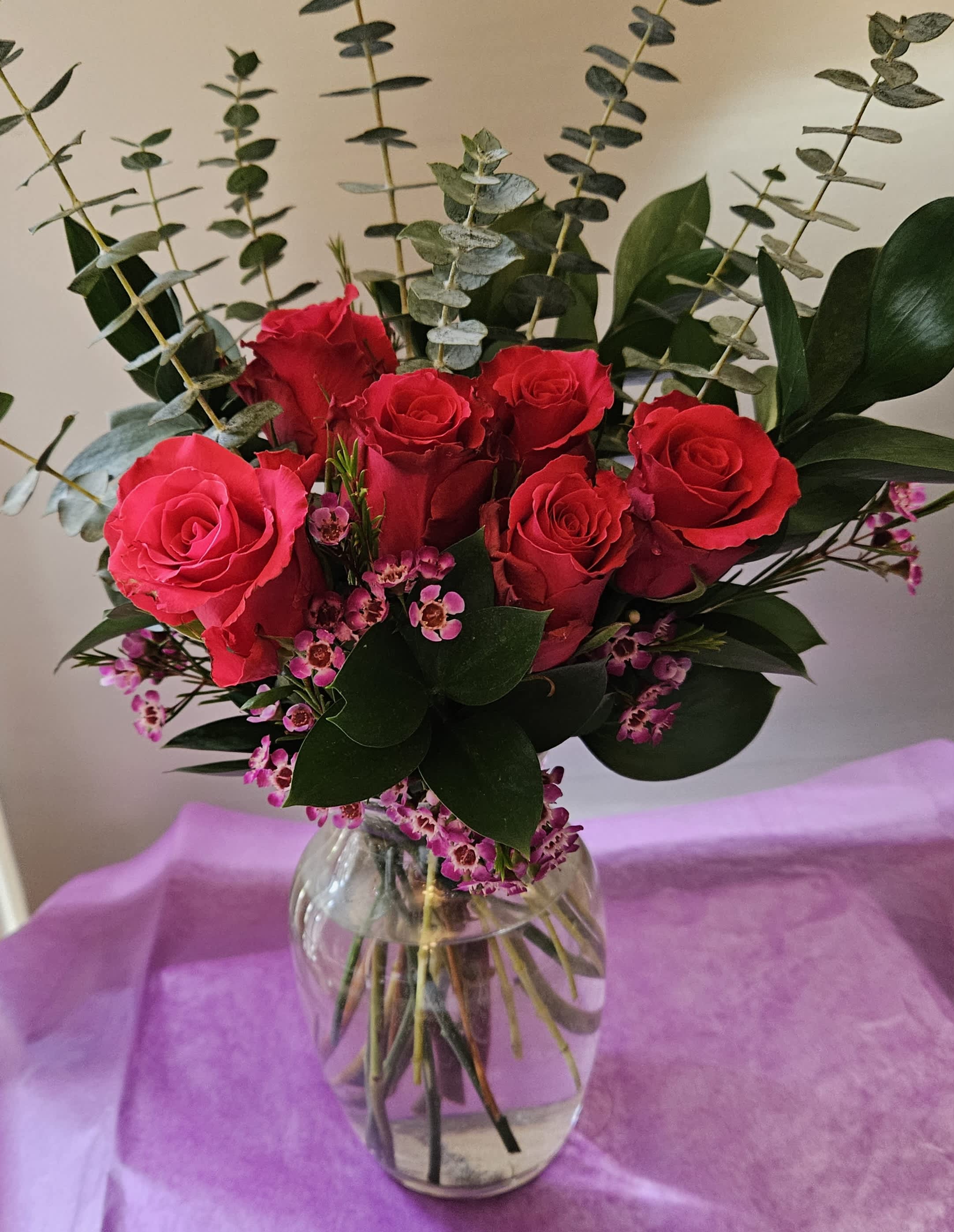Red roses in a clear glass vase with pink filler flowers