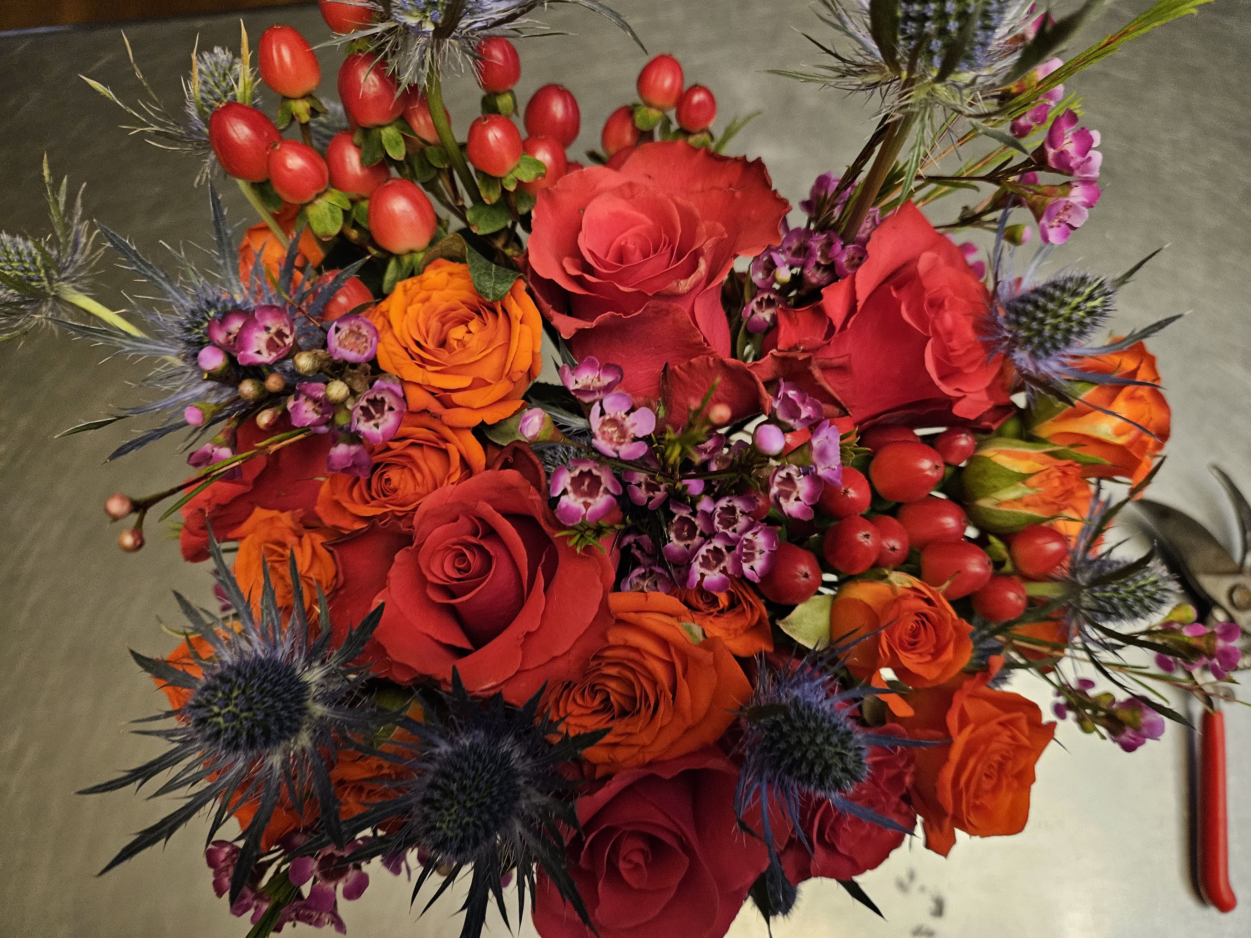 Bouquet of red and orange roses with purple thistle-like flowers