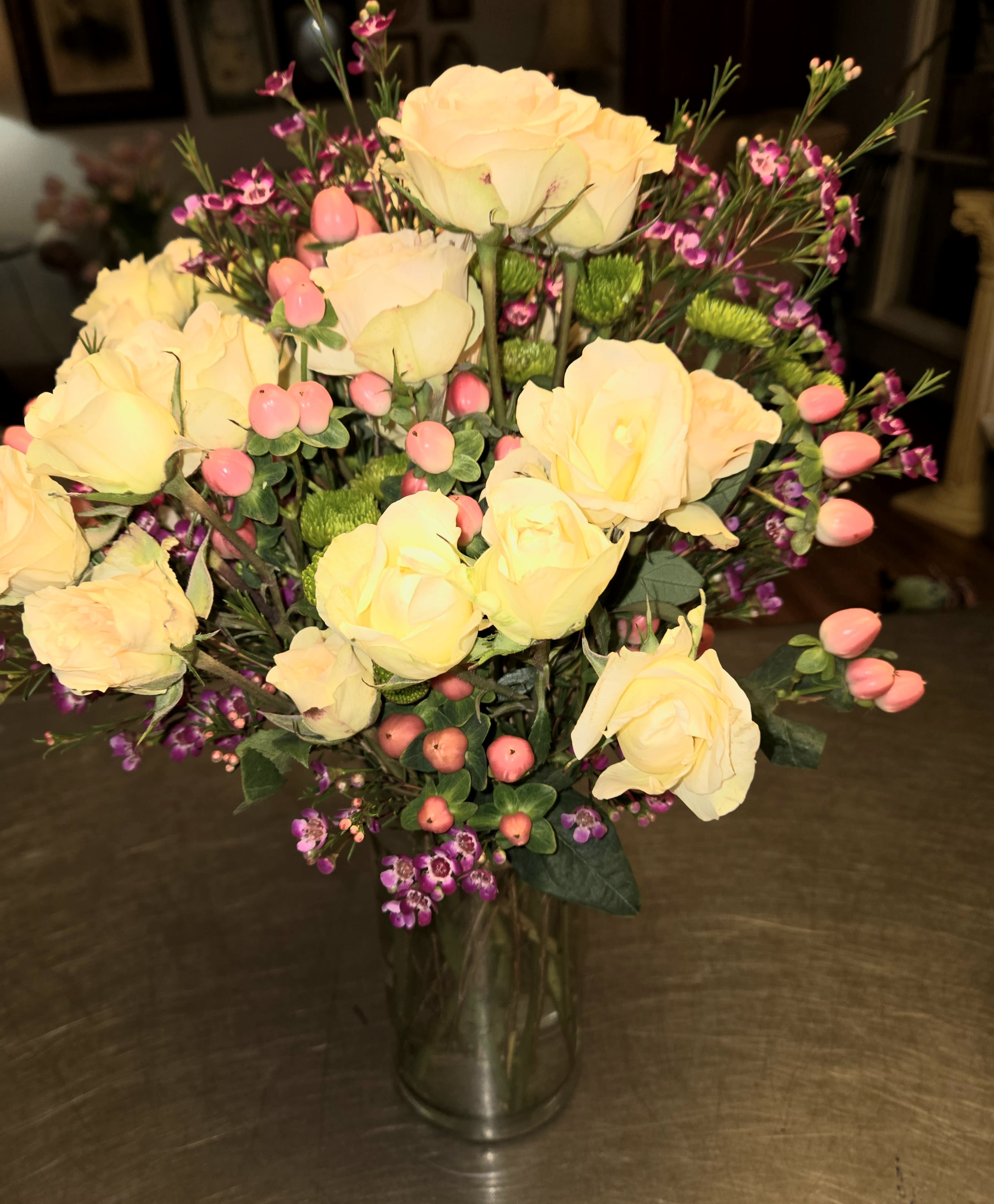 Yellow roses in a clear glass vase with pink filler flowers