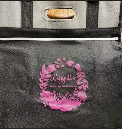 Black insulated tote bag with a pink floral shop logo