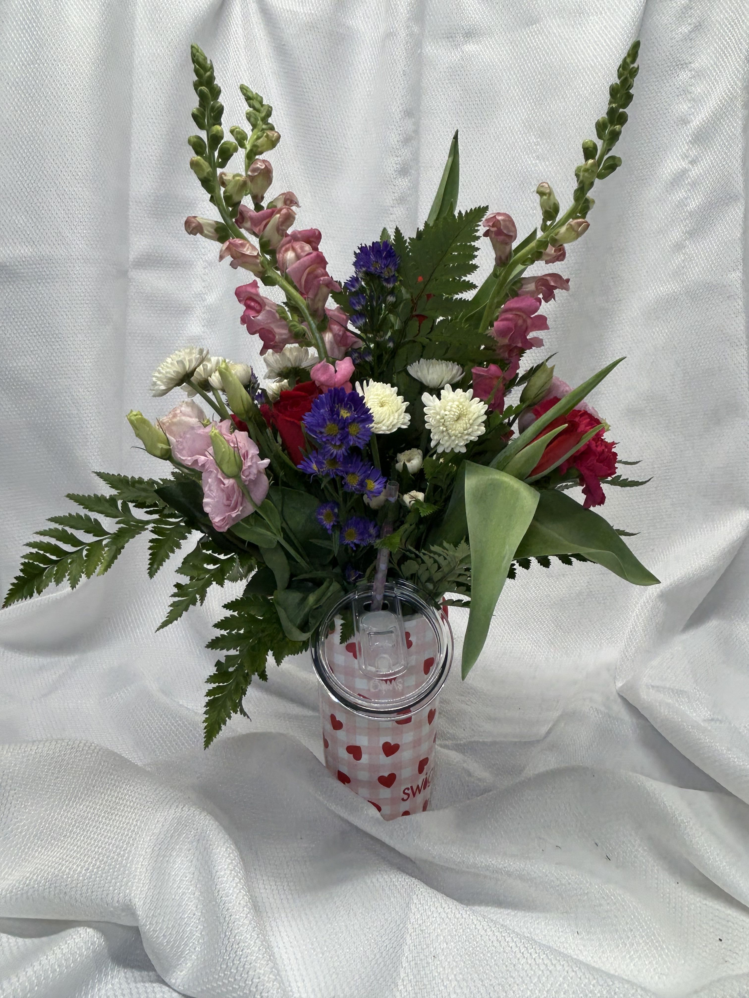 Cuddles - Pink snap dragon, white button mums, pink lisianthus, red tulips, hot pink carnations, red roses &amp; purple monte casino in a swig cup. Cups are dishwasher safe.