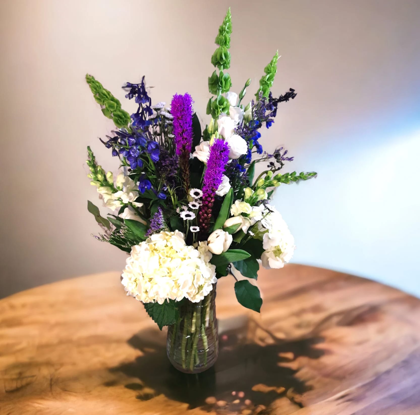 Tall mixed bouquet in a glass vase with white and purple flowers