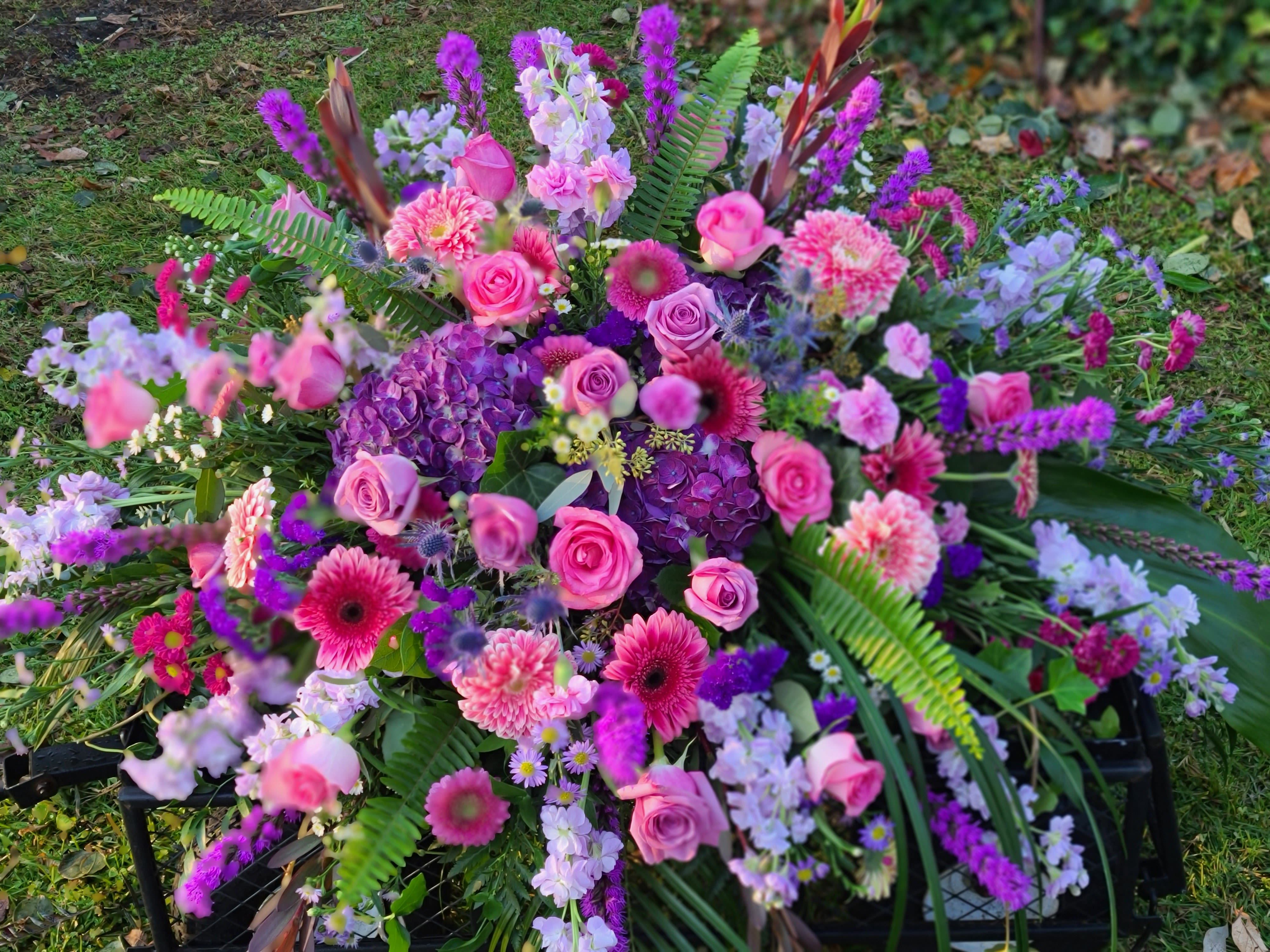 Large pink and purple floral arrangement with roses and mixed blooms