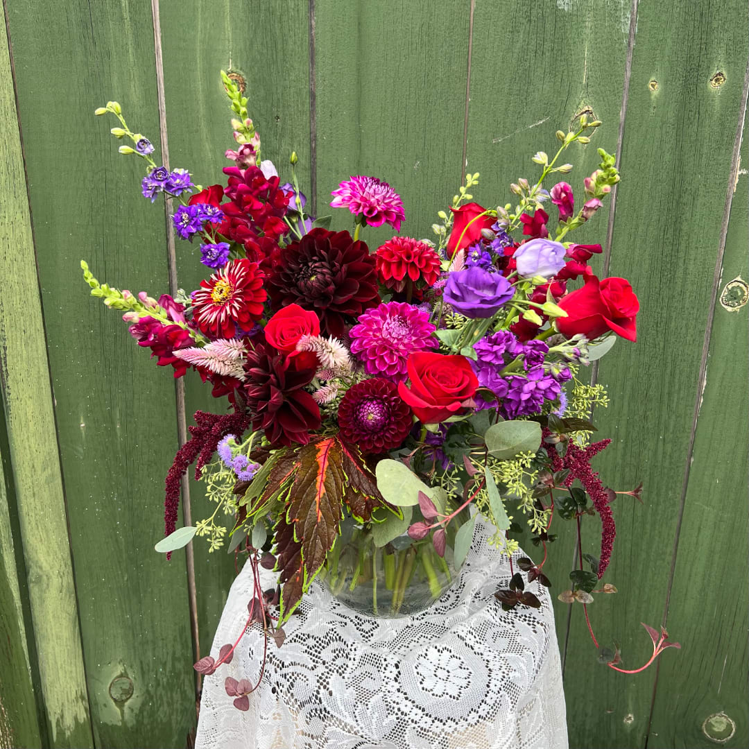 Mixed bouquet of red, purple, and pink flowers in a glass vase