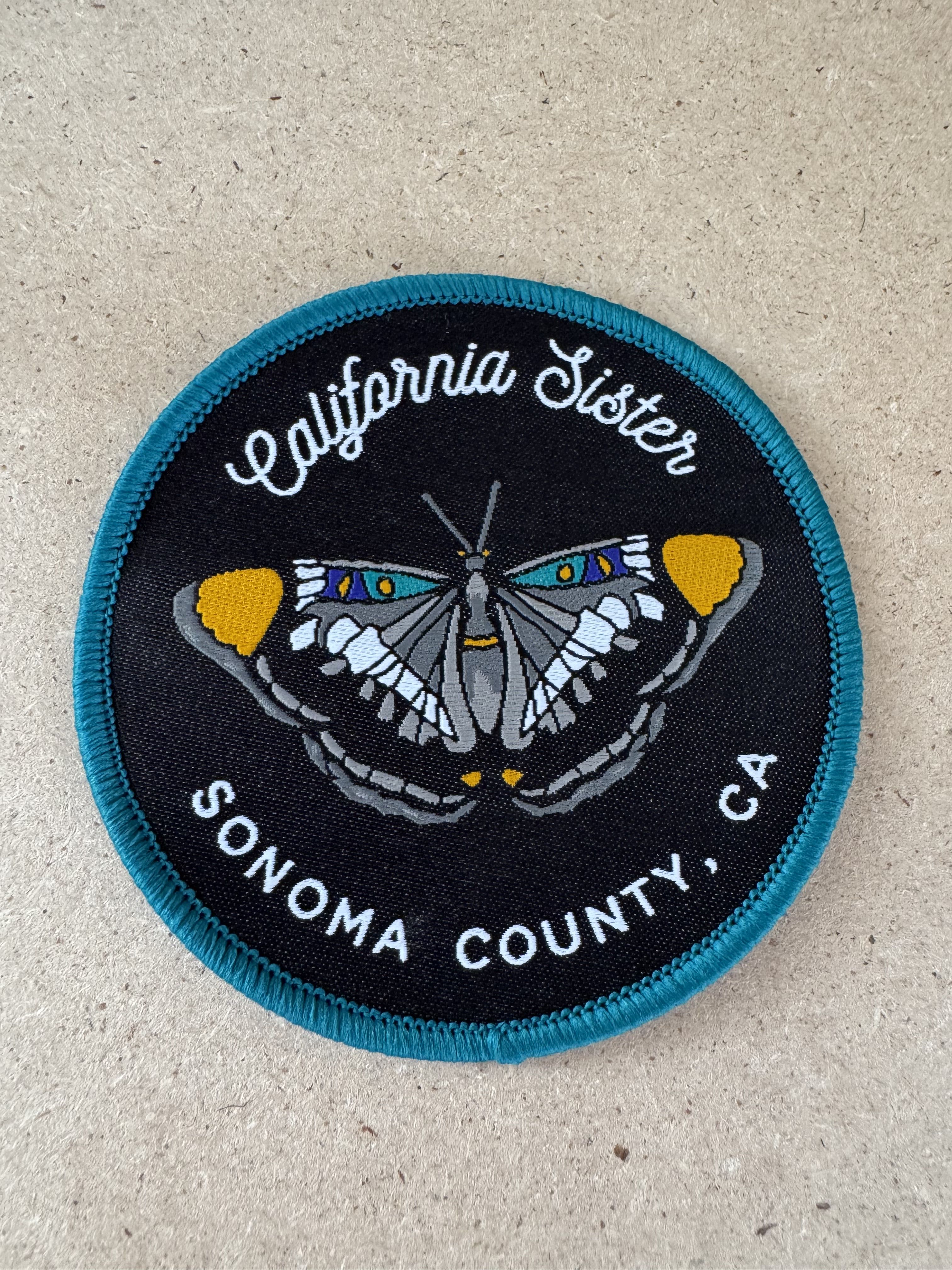 Round California Sister patch with a butterfly design and text
