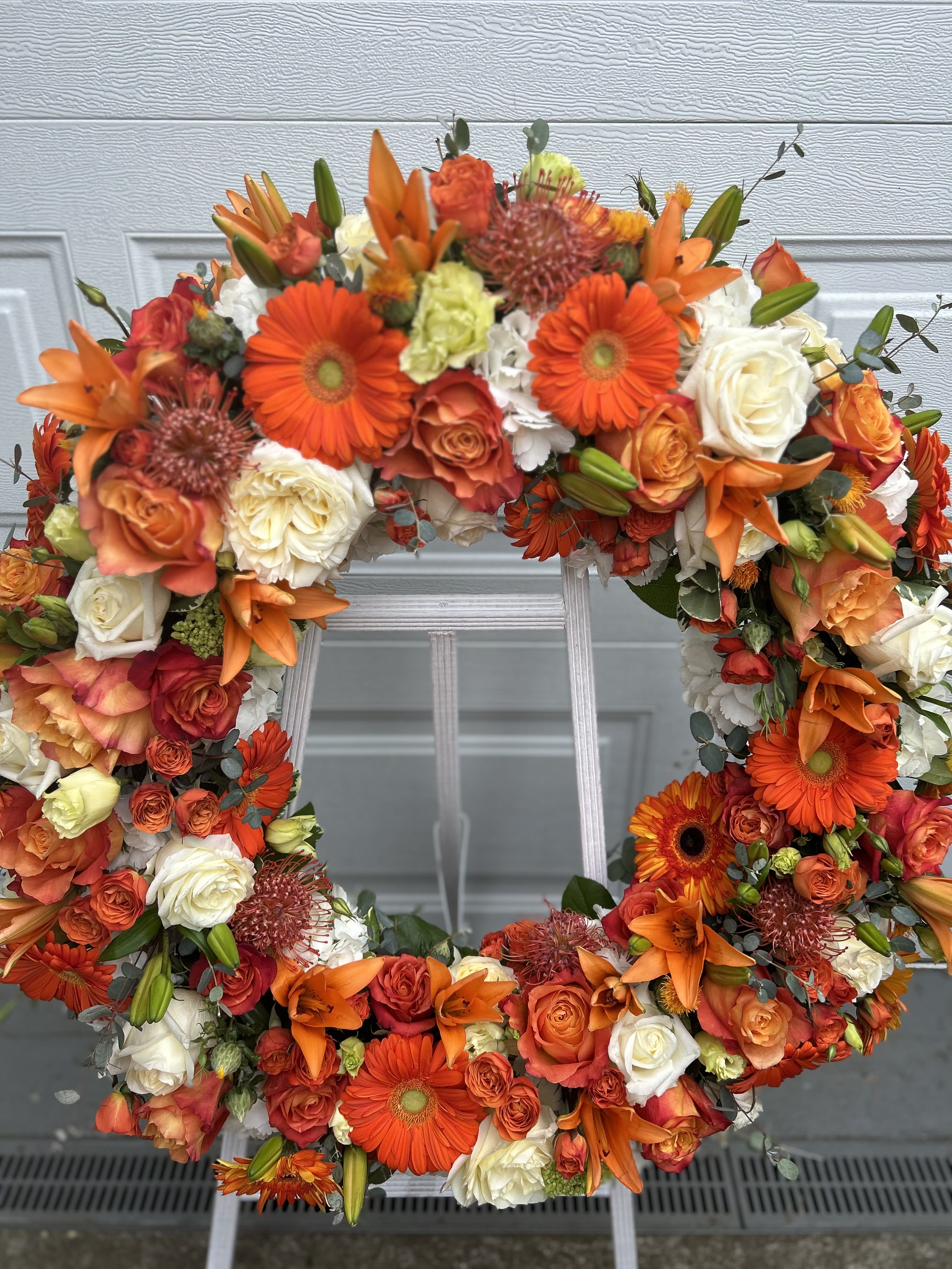 Orange and white floral wreath with roses and lilies