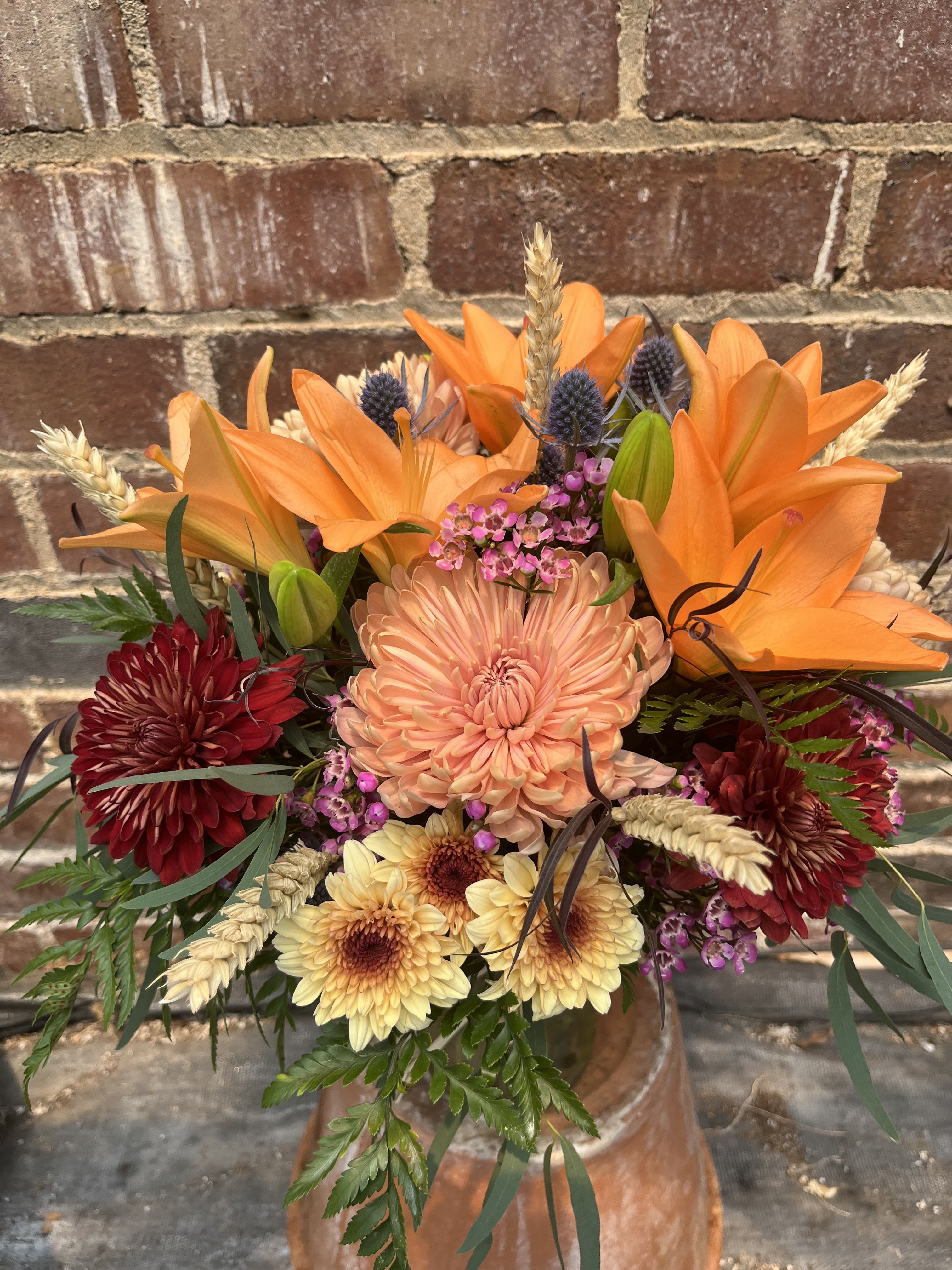 Canyon Sunset - Lilies, chrysanthemums, thistle, accent flowers, dried wheat, and assorted greenery. Arranged in a glass vase.