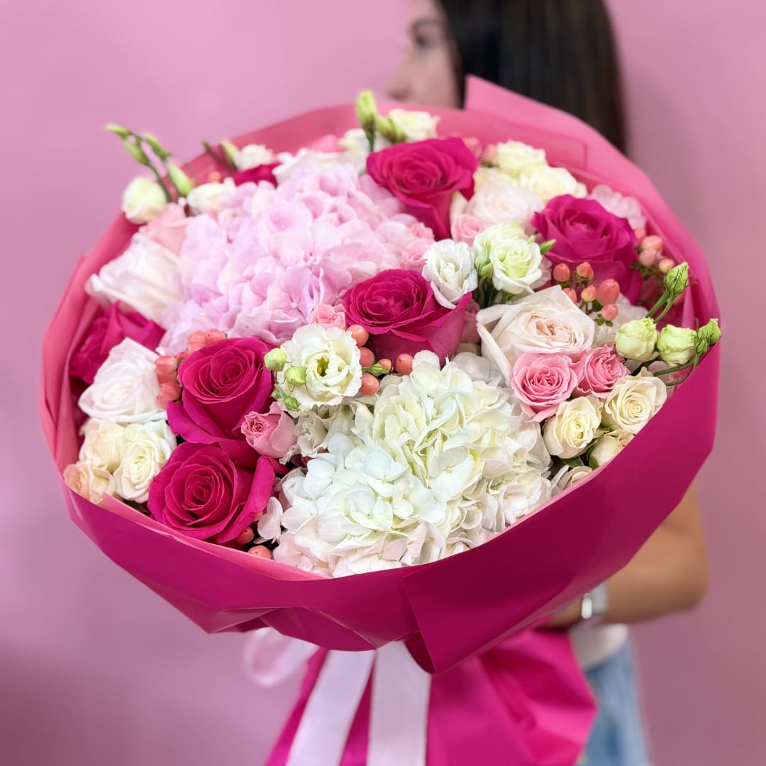 Pink and white bouquet of roses and hydrangeas wrapped in magenta paper