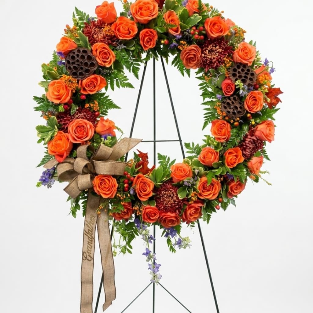 Orange rose wreath on a black stand with a burlap bow
