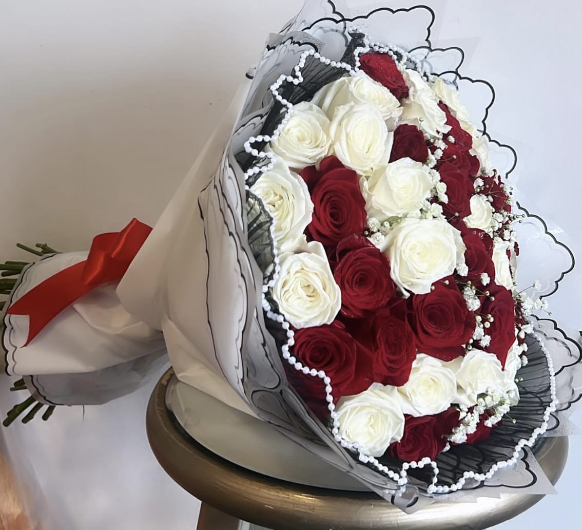 Bouquet of red and white roses wrapped in black-and-white paper with a red ribbon
