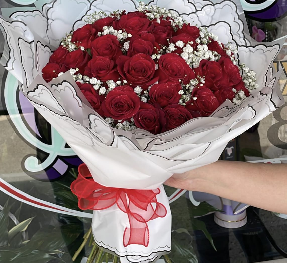 Bouquet of red roses with white baby's breath in white wrapping and a red ribbon