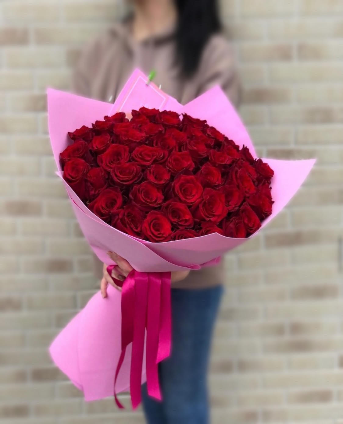 Large bouquet of red roses wrapped in pink paper with a ribbon