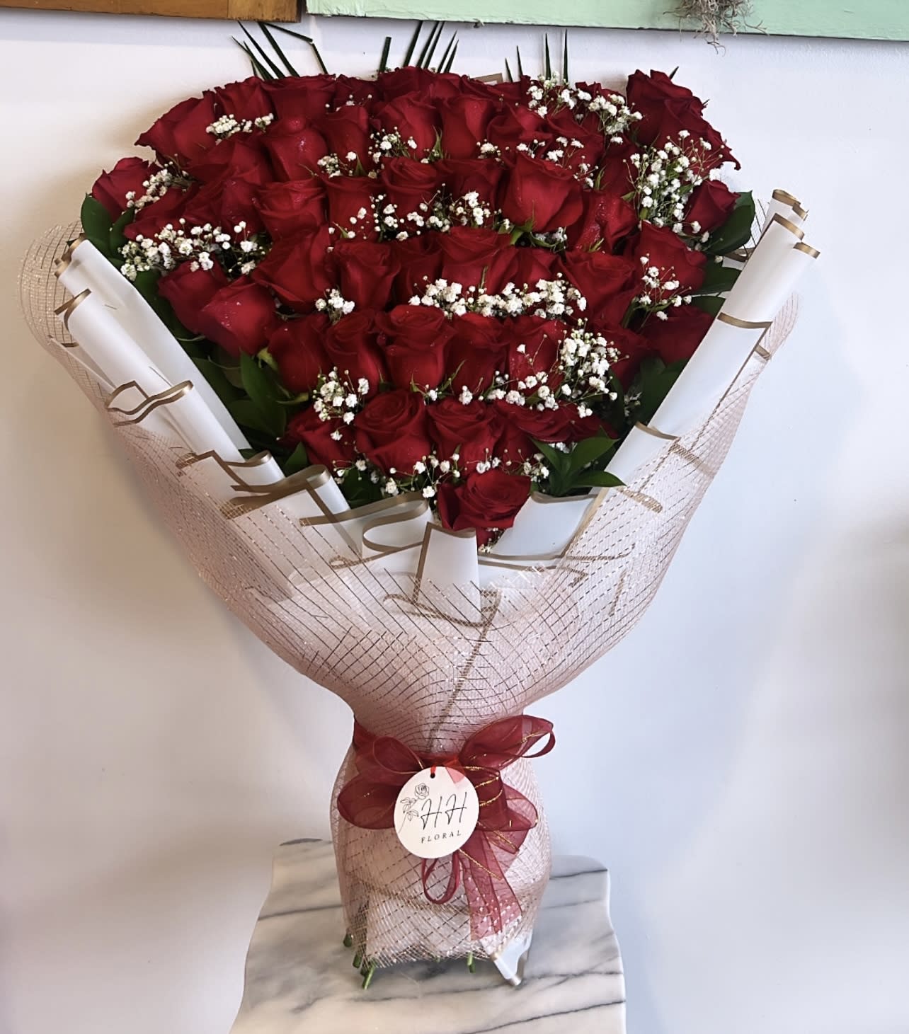 Bouquet of red roses with baby's breath wrapped in pink mesh
