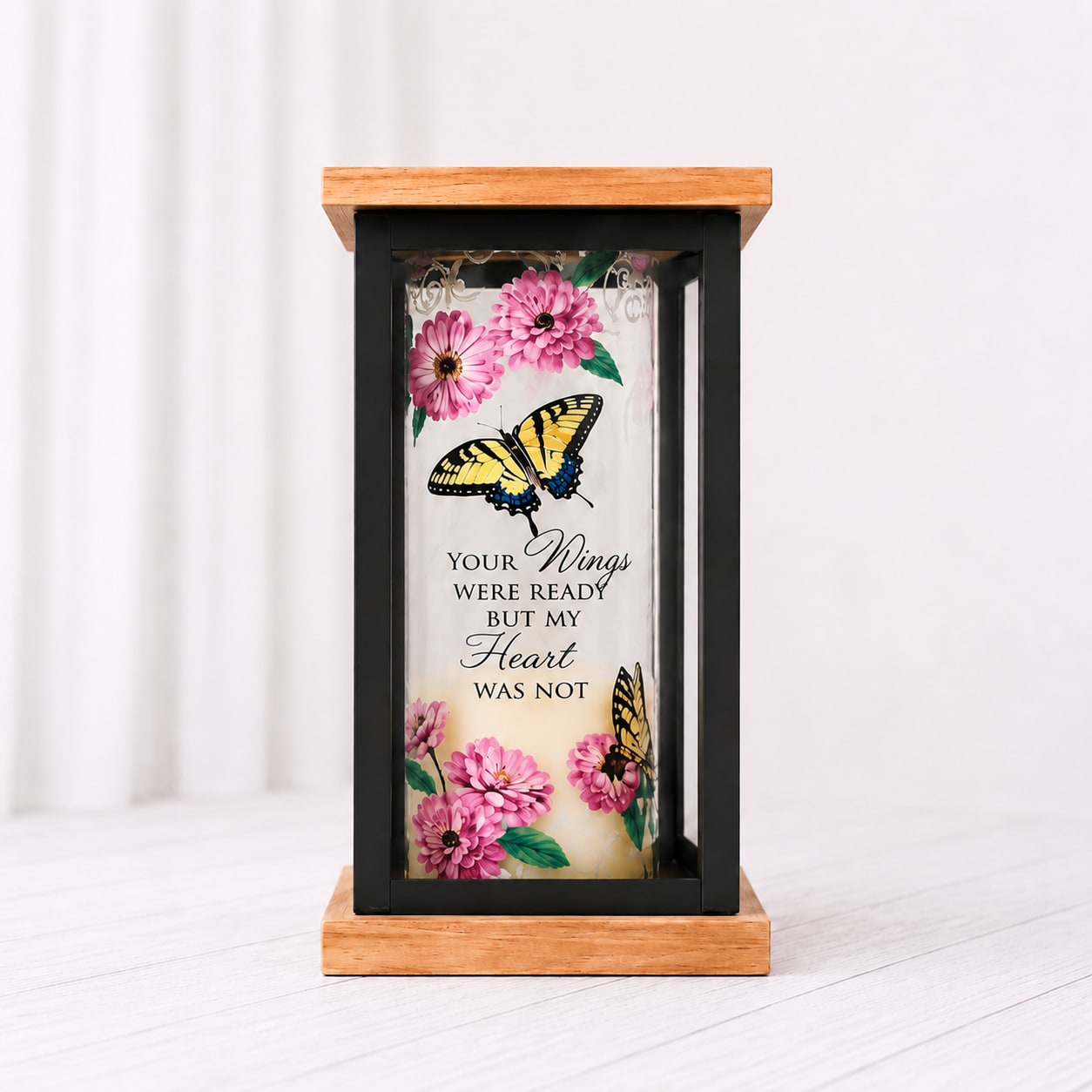 Candle Lantern  - The Memories &amp; Light Sympathy Lantern is a heartfelt keepsake designed to bring comfort, remembrance, and peace to those grieving the loss of a loved one. Each one features soft LED candlelight, meaningful memorial sentiments, and delicate nature-inspired artwork including florals, butterflies, and songbirds. Finished with a warm wood and black metal design, these lanterns make thoughtful sympathy gifts, memorial décor pieces, or comforting reminders that love and memories live on forever. includes batteries and a bow. 8.5" tall. 