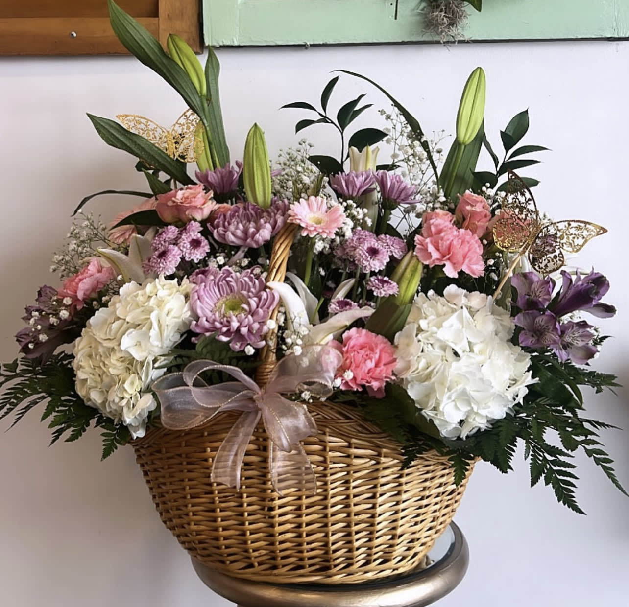 Basket arrangement of pink, white, and purple flowers with lilies and hydrangeas