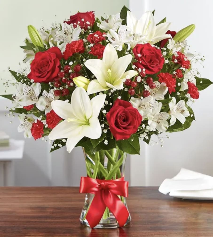 Red roses and white lilies in a glass vase with a red ribbon