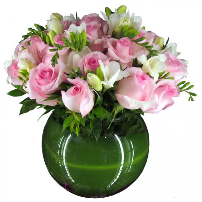 Pink roses and white flowers arranged in a green glass vase