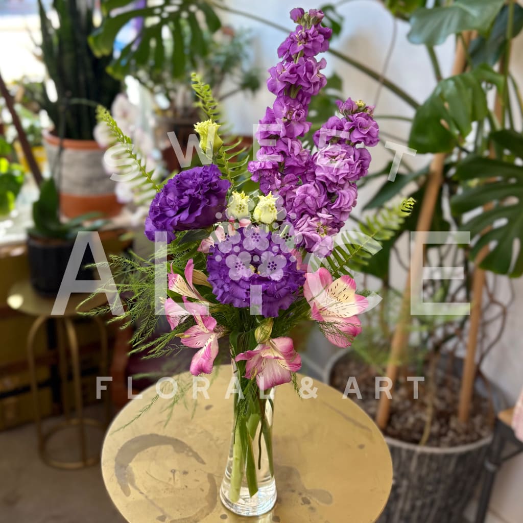 Purple Paradise - A lovely mix of purple hued blooms, paired with tropic ferns.  Lightly scented, bringing that sweet paradise smell directly to those you hold dear.
