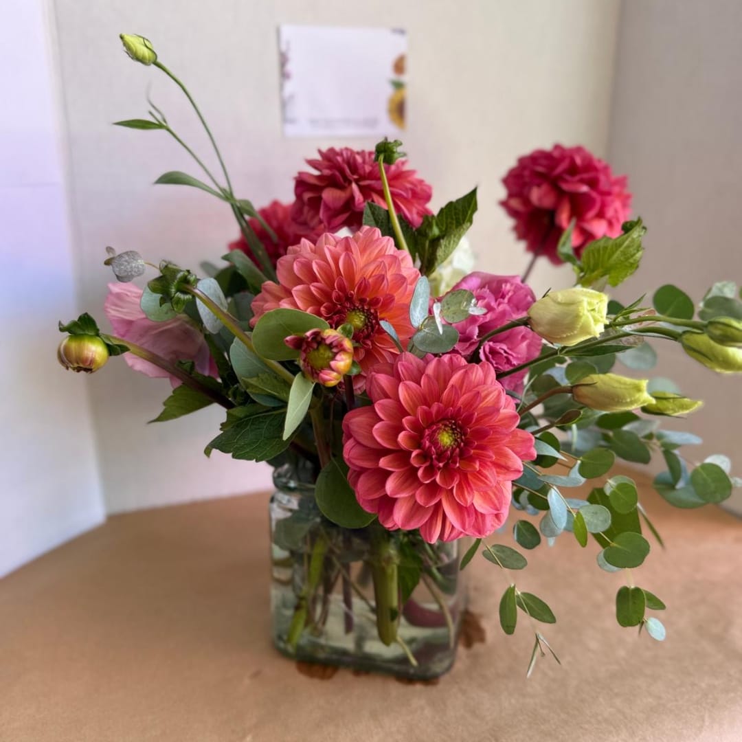 Pink and coral flowers arranged in a clear glass vase