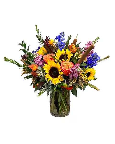 Mixed bouquet with sunflowers, roses, and blue flowers in a glass vase