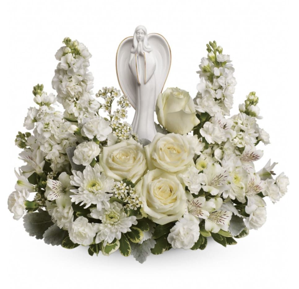 White floral arrangement with roses and a praying angel figurine
