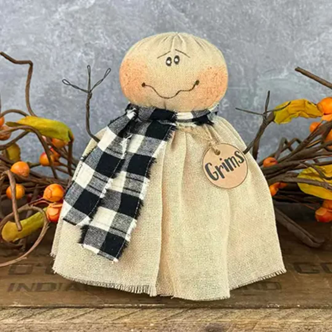 Decorative scarecrow figurine with a plaid scarf and tag