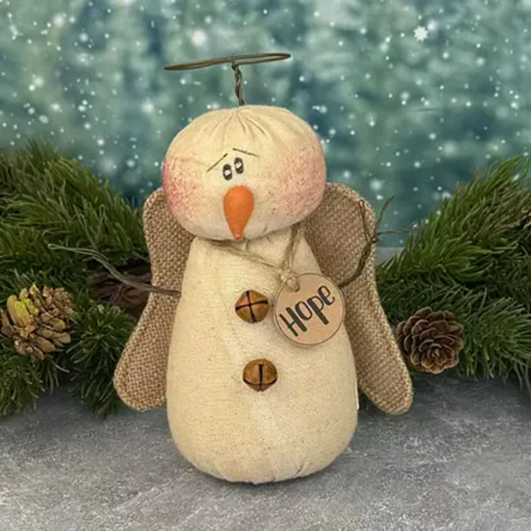 Decorative angel figurine with a "Hope" tag, pinecones, and evergreen branches