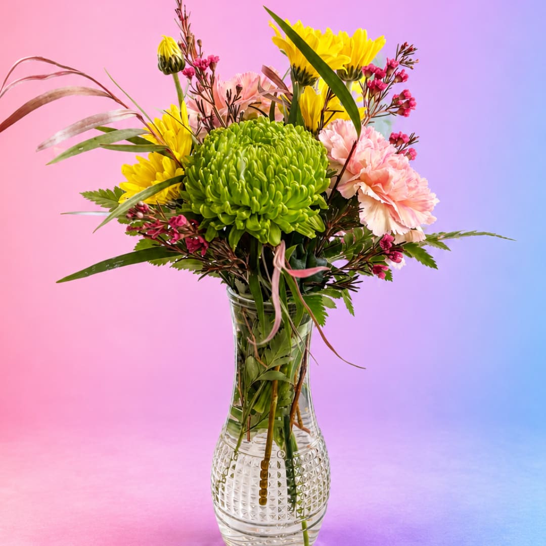 Mixed bouquet in a clear glass vase with green, yellow, and pink blooms